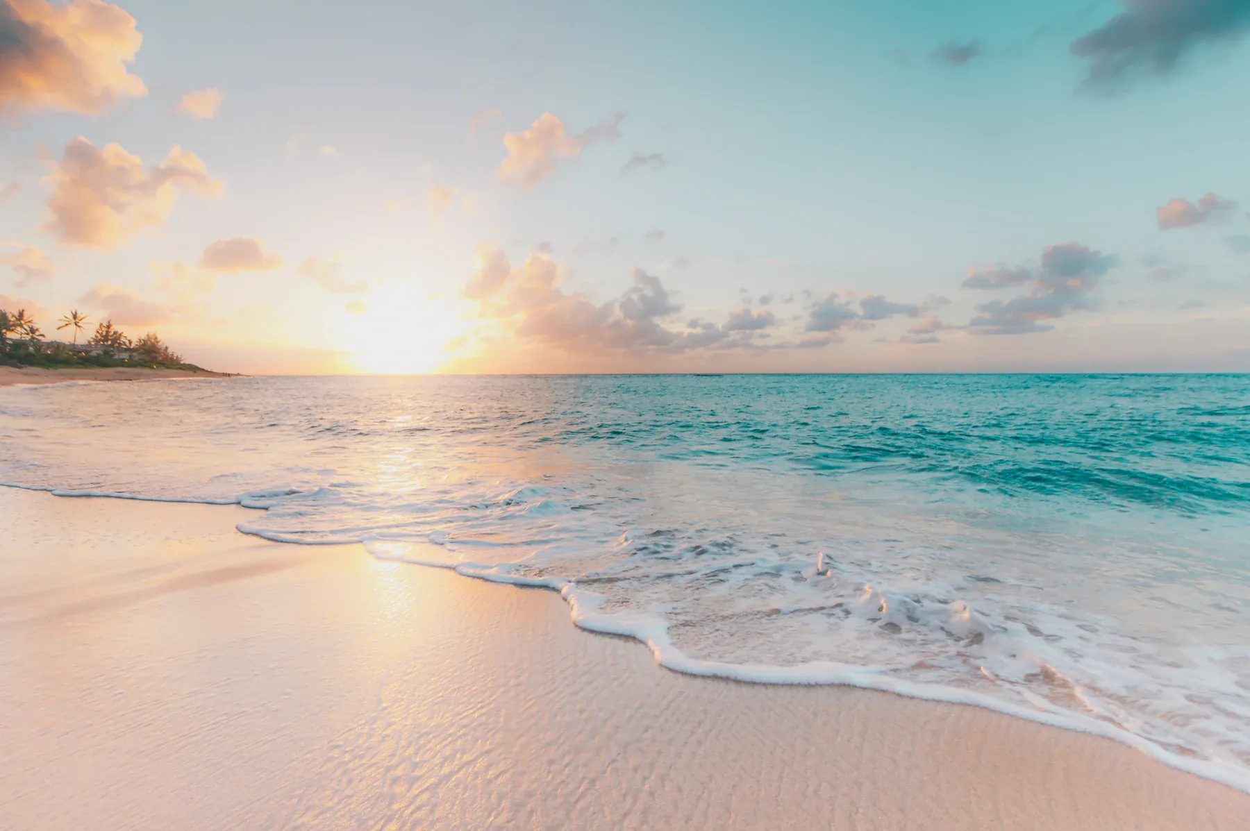 A pale shoreline meeting calm blue water at dawn